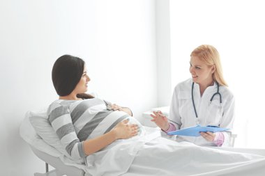Hastanede genç hamile bir kadın ve doktor.
