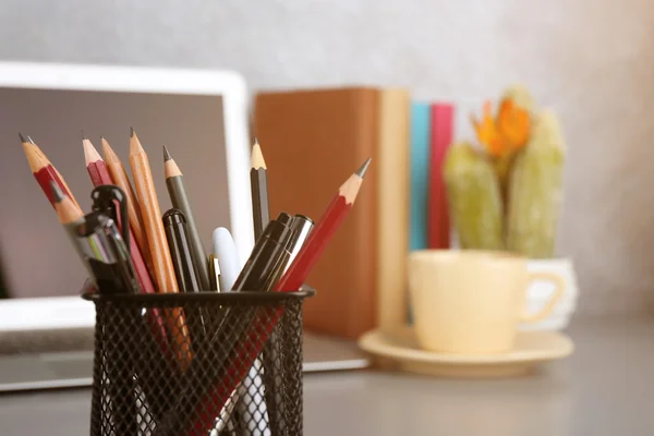 Tužky a pera v kovovém držáku s notebookem — Stock fotografie
