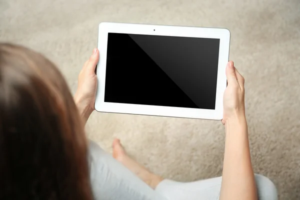 Frau hält Tablet auf verschwommenem Teppich-Hintergrund — Stockfoto