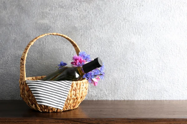 Wine bottle with flowers in basket — Stock Photo, Image