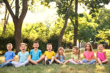 Mutlu çocuklar parkta çim üzerinde oturan