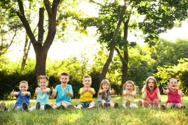 Mutlu çocuklar parkta çim üzerinde oturan