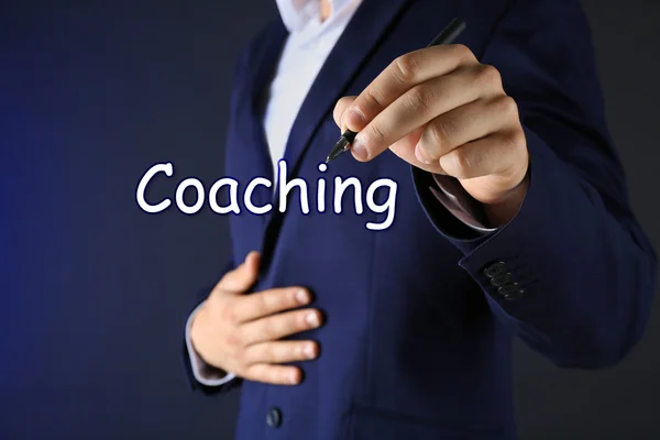 Leadership coaching concept. Businessman in suit with pen on dark background — Stock Photo, Image