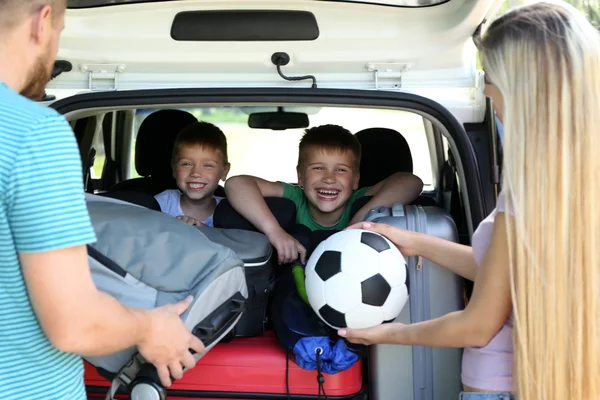 Padres poniendo equipaje en el maletero del coche —  Fotos de Stock