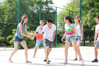 Gençler açık havada basketbol oynarken