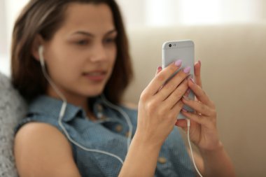 Kız akıllı telefon ve kulaklık ile müzik dinlemek