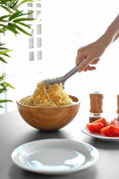 Hand putting pasta on plate — Stock Photo, Image