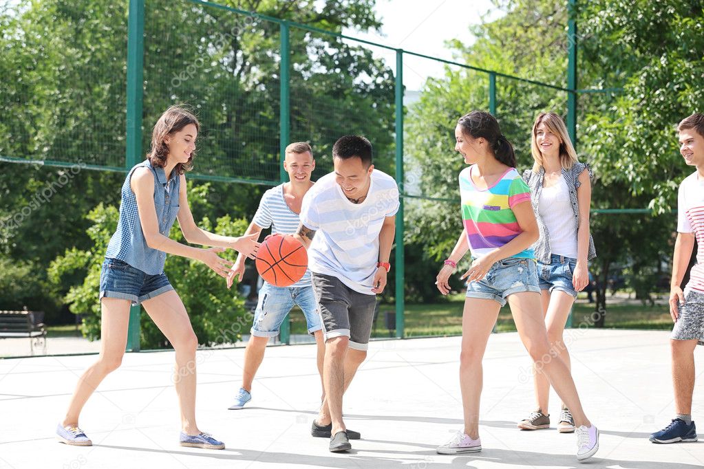 Teenagers playing basketball outdoors