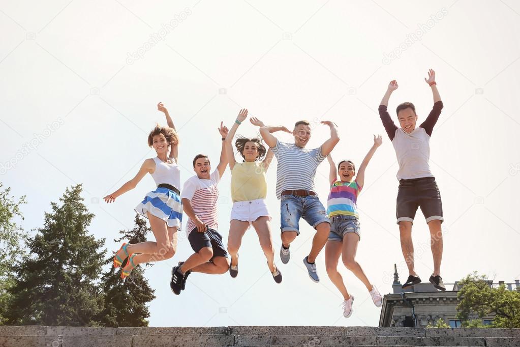 Group of happy teenagers jumping on street