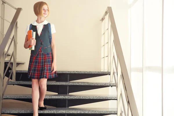 Söt skolflicka med böcker om trappor — Stockfoto