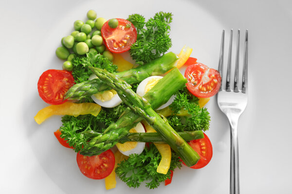 Спаржа с овощами на тарелке
