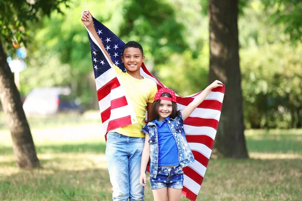 Chlapec a dívka drží Americká vlajka — Stock fotografie