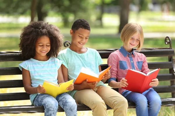 Lindos niños leyendo libros en el banco — Foto de Stock