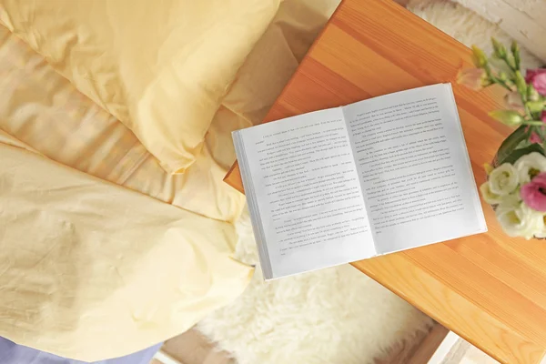 Aufgeschlagenes Buch auf hölzernem Bett — Stockfoto