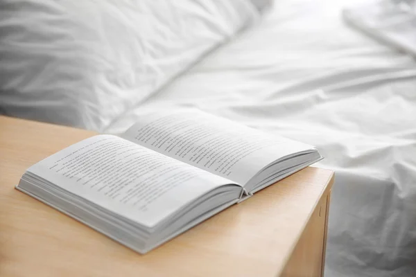 Aufgeschlagenes Buch auf hölzernem Bett — Stockfoto