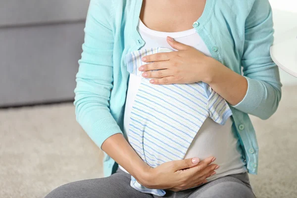 Mulher grávida com roupas de bebê — Fotografia de Stock