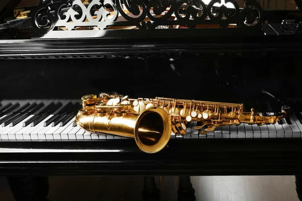 Saxofon liggande på piano — Stockfoto