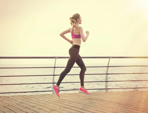 Young woman running on pier — Stock Photo, Image