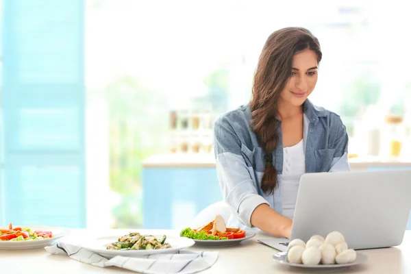 Menina na cozinha com laptop — Fotografia de Stock