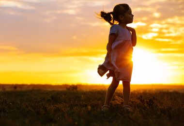 Sevimli kız siluet günbatımı arka plan üzerinde