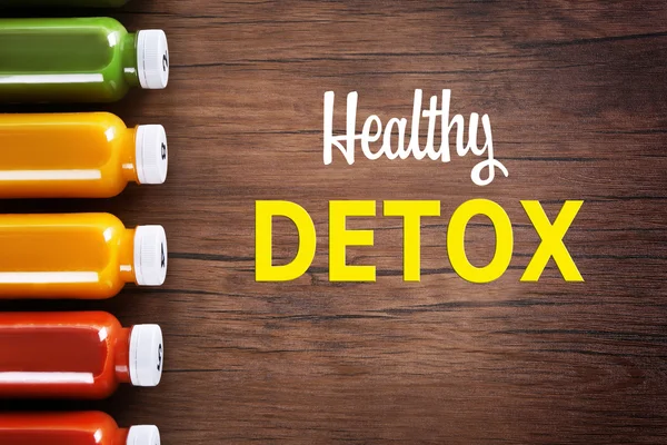 Bottles with delicious detox drinks and text healthy detox on wooden background. Detox diet concept. — Stock Photo, Image