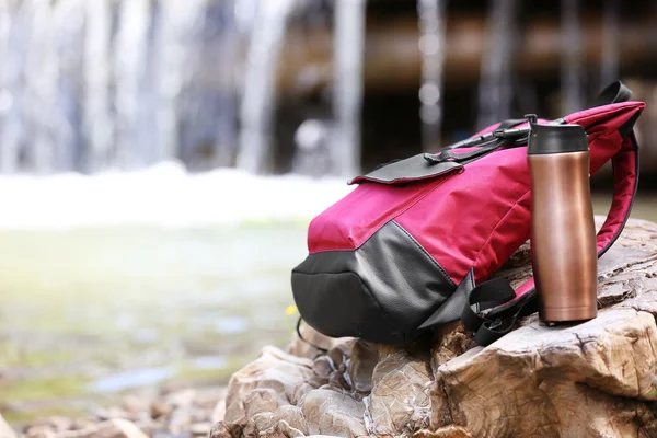 Backpack and bottle on stone — Stock Photo, Image