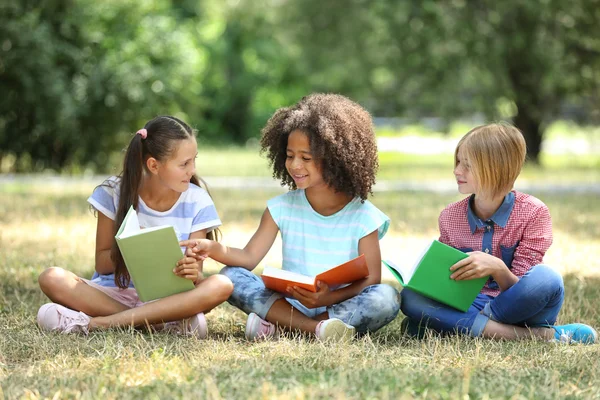 Enfants mignons lisant des livres sur l'herbe verte — Photo