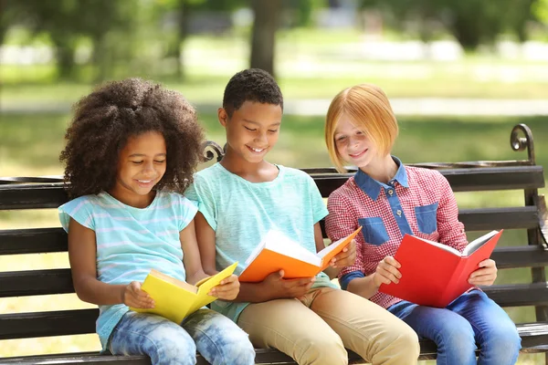 Cute kids reading books on bench Royalty Free Stock Photos