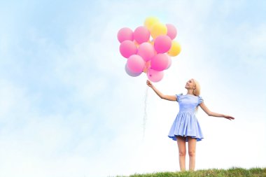 Güzel genç bir kadın elinde balonlarla 