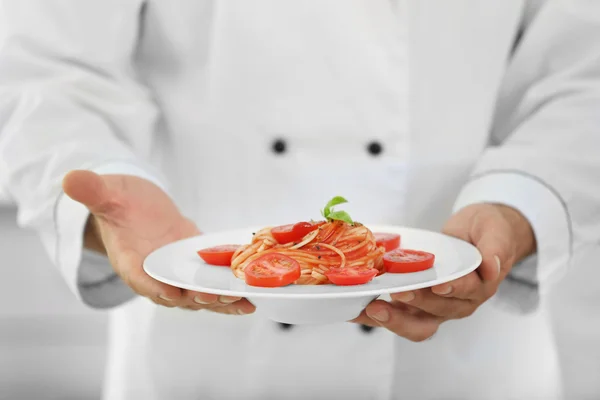 Chef in possesso di piatto di deliziosa pasta in cucina — Foto Stock