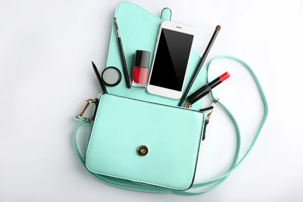 Bolsa de maquiagem com produtos de beleza e telefone no fundo branco — Fotografia de Stock