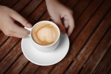 Ahşap masa üzerinde taze kahve tutan eller