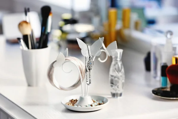 Suporte de jóias com conjunto de cosméticos na mesa de vestir leve — Fotografia de Stock
