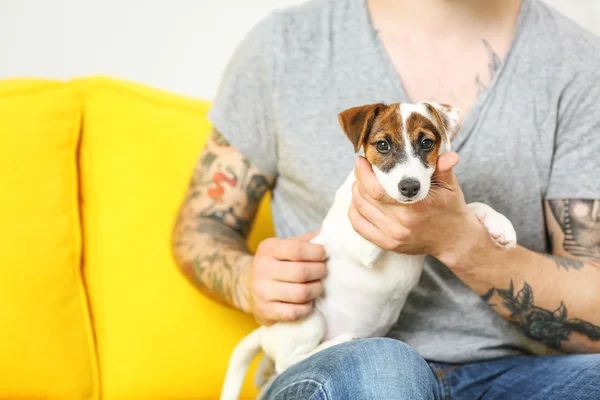 Mann mit niedlichem Hund auf gelbem Sofa — Stockfoto