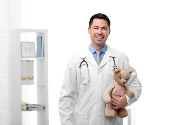 Médico pediatra con osito de peluche en consultorio —  Fotos de Stock