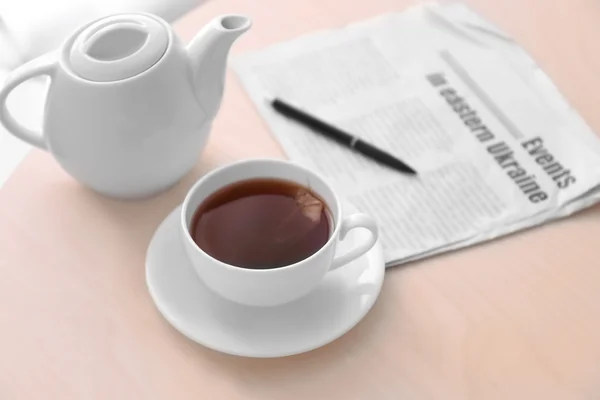 Filiżanka herbaty z gazetą na stole — Zdjęcie stockowe