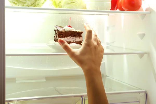 Vrouwelijke hand die reikt voor de smakelijke taart. Ongezond voedsel concept — Stockfoto