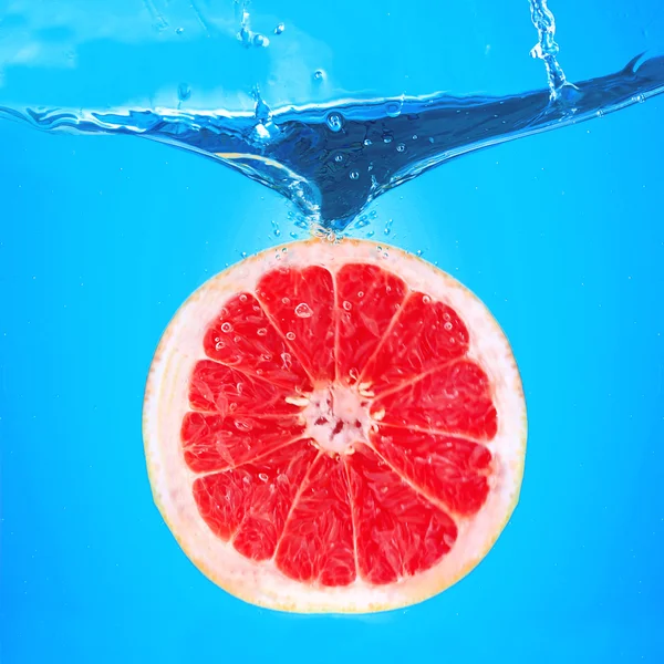 Fresh grapefruit falling in water — Stock Photo, Image