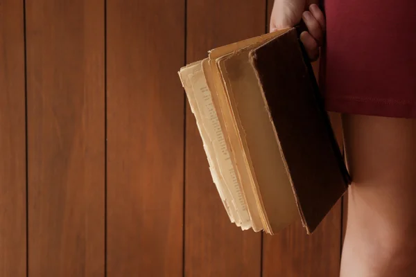 木製の背景上の古い本を保持している女性 — ストック写真