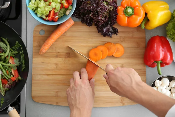 Женские руки режут морковь — стоковое фото
