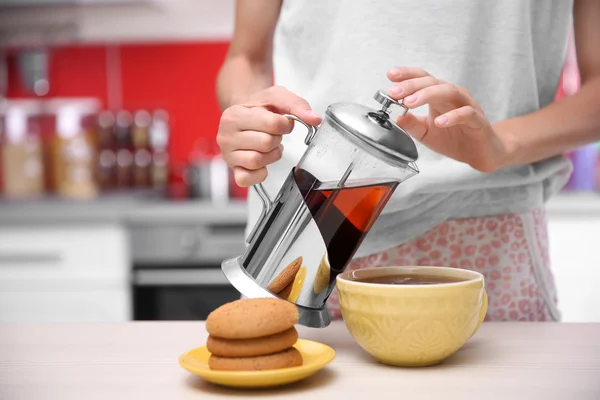 Mulher dando um pouco de chá na cozinha — Fotografia de Stock