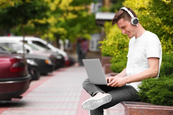 Homme avec ordinateur portable écouter de la musique sur la rue — Photo