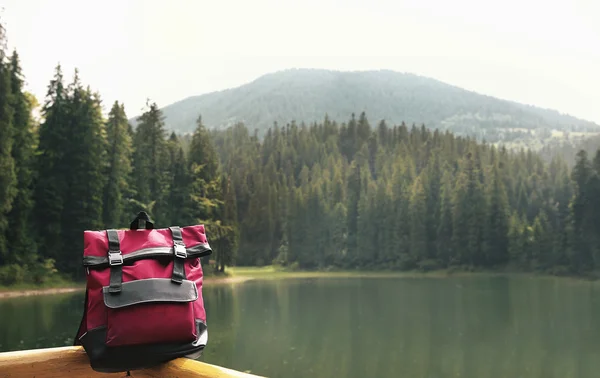 Red backpack on mountain lake