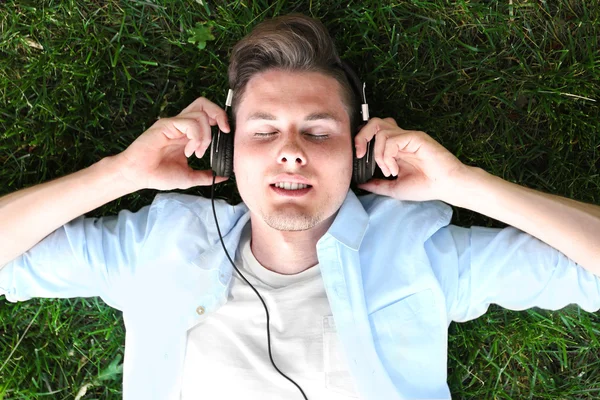 Muž poslech hudby na zelené trávě — Stock fotografie