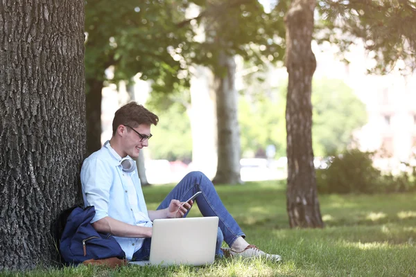 Homem com laptop ouvindo música no parque — Fotografia de Stock