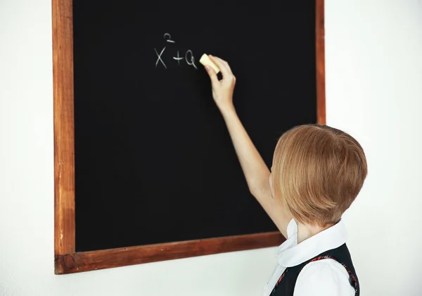 Schoolmeisje schrijven op schoolbord — Stockfoto