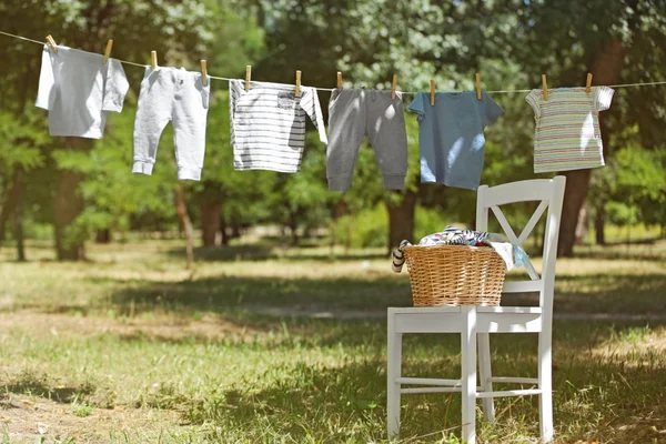 Wicker basket on white chair and baby laundry — Stock Photo, Image