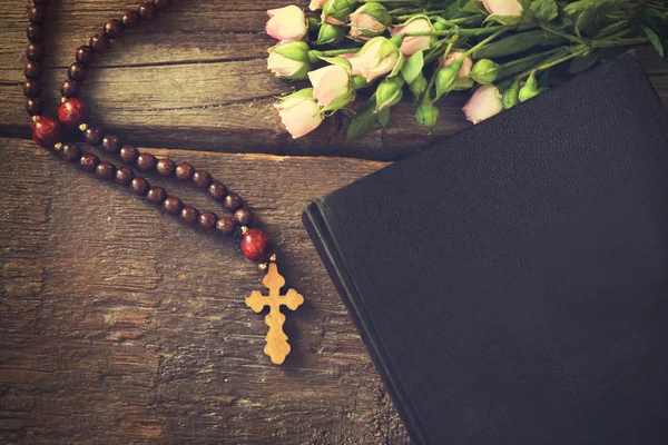 กางเขนไม้ที่มีดอกไม้และพระคัมภีร์ไบเบิลศักดิ์สิทธิ์ — ภาพถ่ายสต็อก