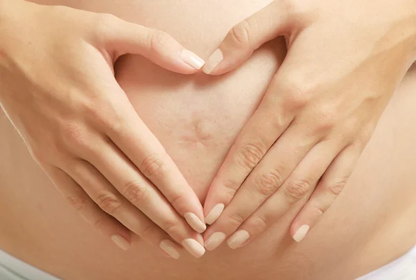 Pregnant woman holding hands on belly — Stock Photo, Image