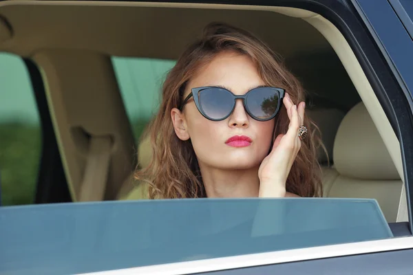 Mujer joven sentada dentro del coche — Foto de Stock